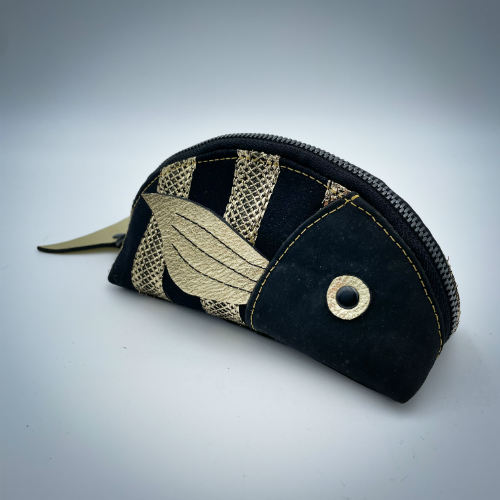 A zippered pouch sewn with black cork, black voile with golden stripes, and golden metallic leather.