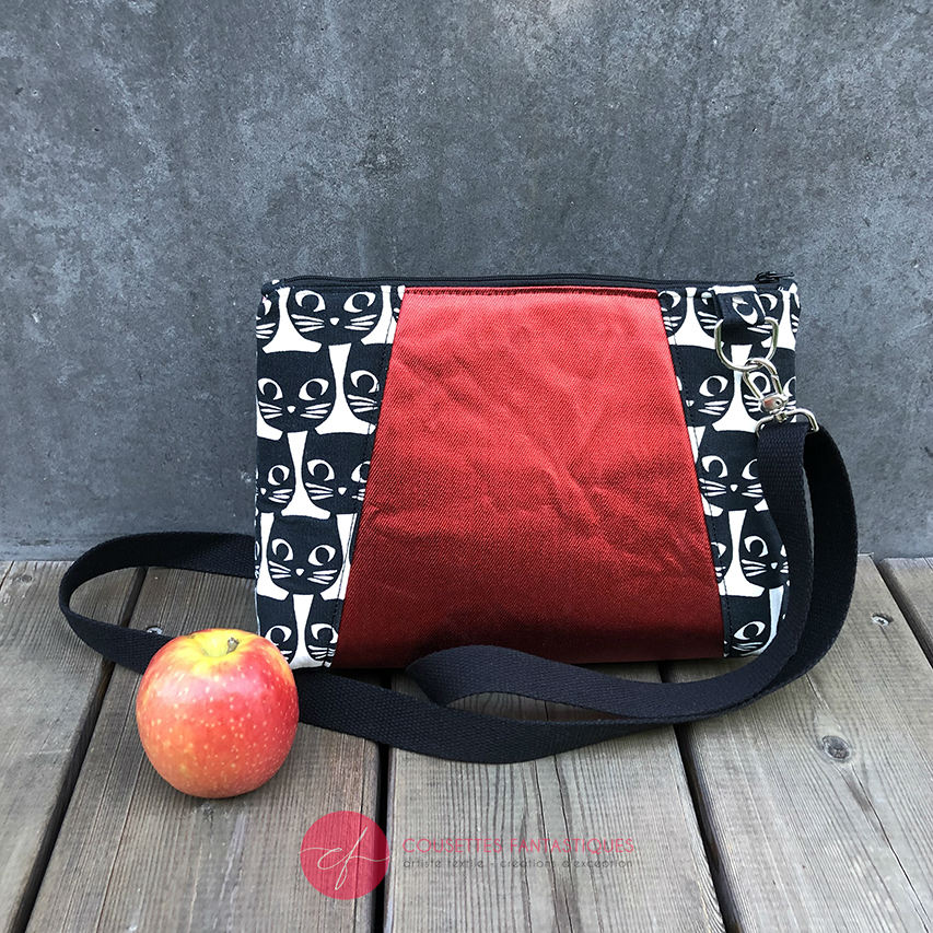 A trapezoid messenger bag made from black and white cotton fabrics on the outside with stylized cat and bird motifs, matched with bird-themed cotton cretonne on the inside.
