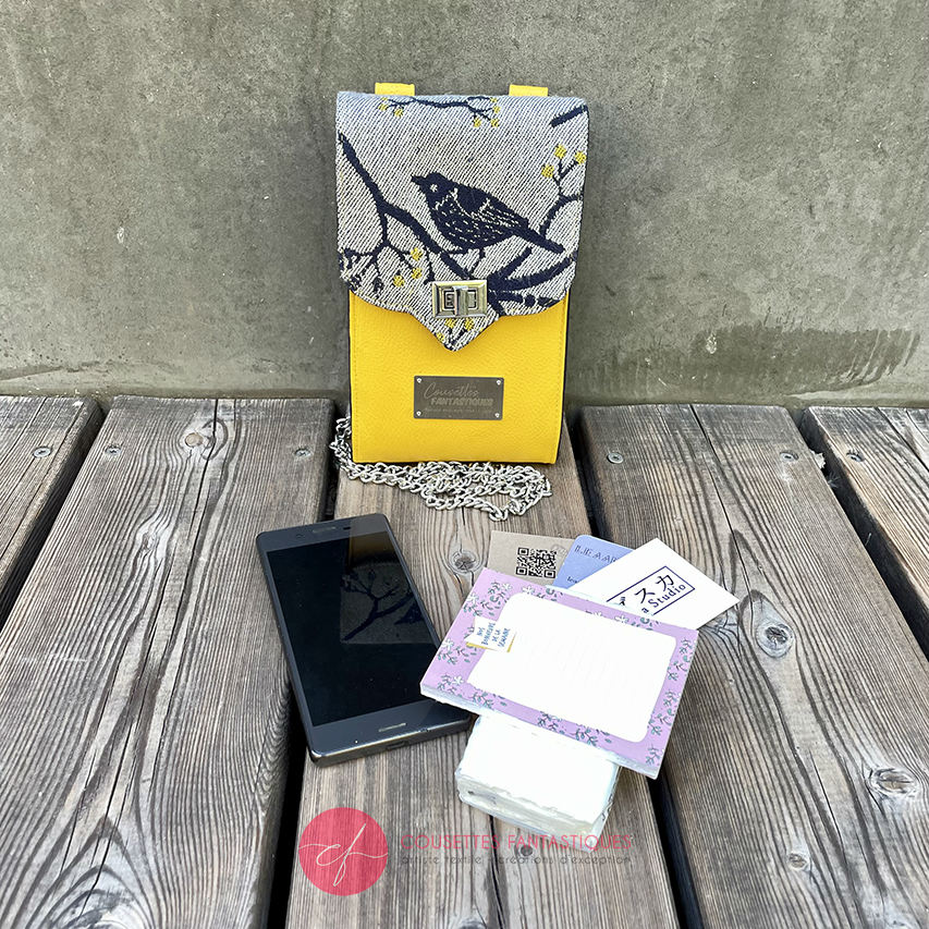A wallet made from a gray, navy blue, and yellow babywearing scarf with bird motifs, and sun-yellow faux leather.