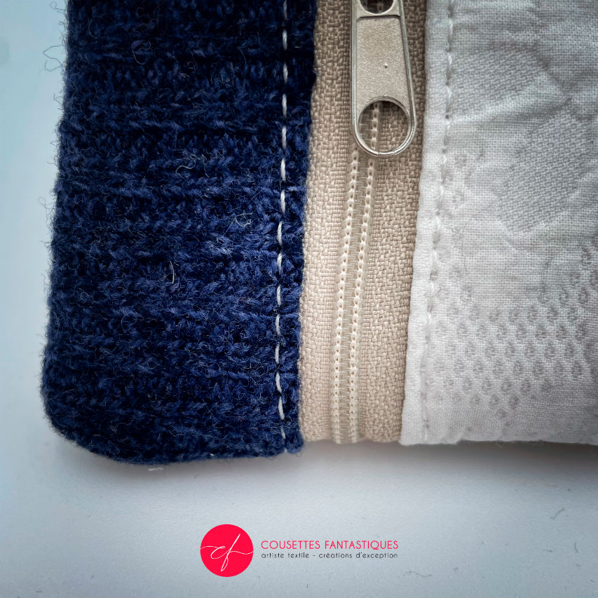A mini zippered coin purse made from navy blue knitted pullover and white damask fabric.
