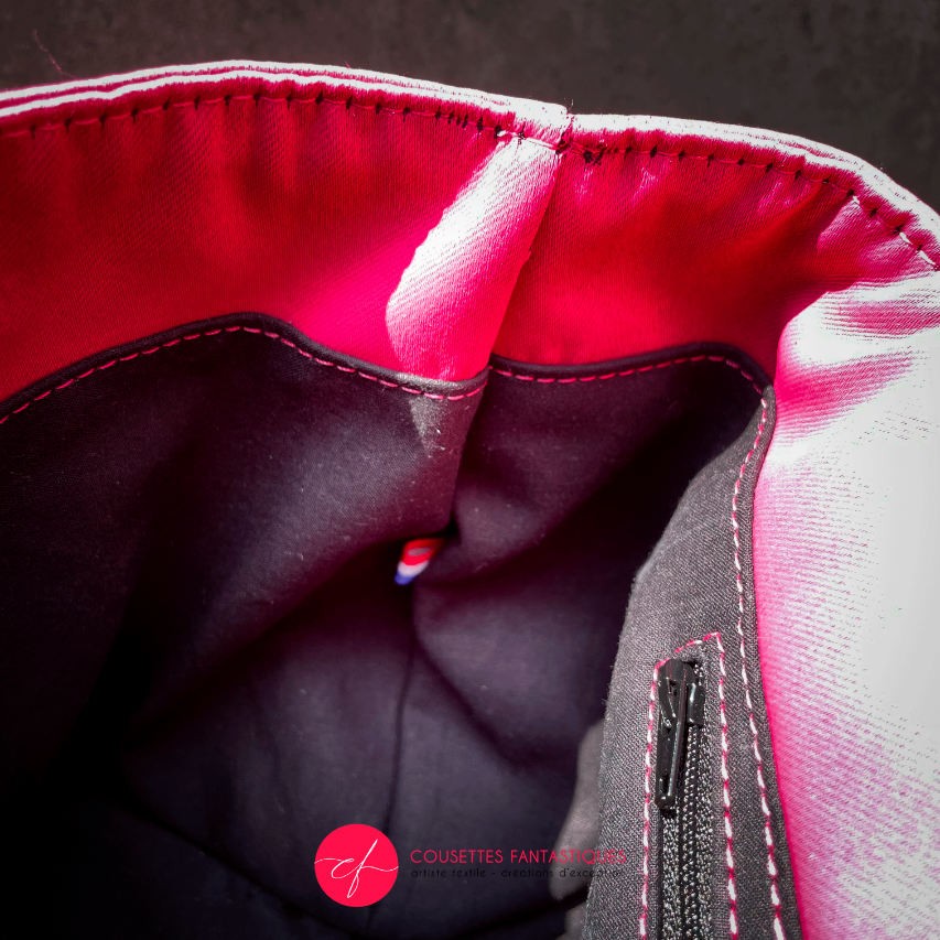 Un sac à dos fabriqué avec un tissu d'ameublement rose vif, du cuir noir et un coupon d'écharpe de portage au motif floral.