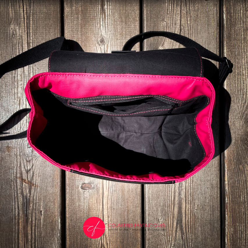 Un sac à dos fabriqué avec un tissu d'ameublement rose vif, du cuir noir et un coupon d'écharpe de portage au motif floral.
