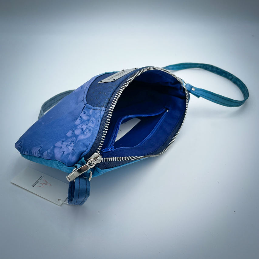 Une pochette zippée cousue dans un foulard en soie dans les tons bleus, plissé et associé à du liège bleur roi.