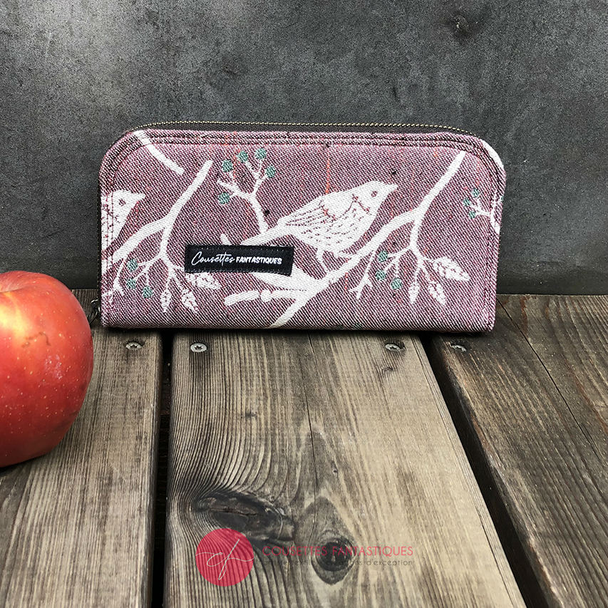 A zippered card and coin holder made with mauve and green bird-patterned babywearing wrap fabric.