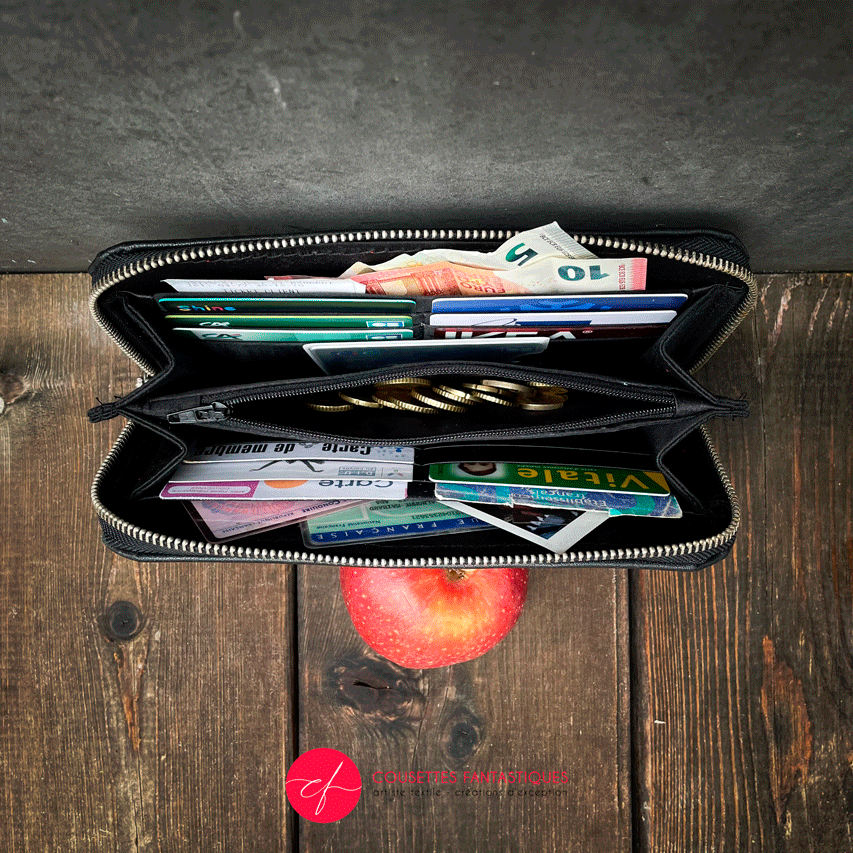 A wallet made from a babywearing wrap in a gradient from blue to violet on the outside and black, pink, and petrol poplin on the inside.