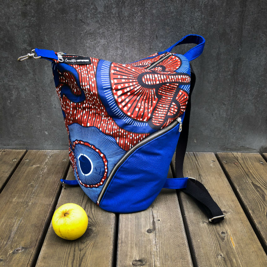 Un sac à dos cousu en toile bleu roi et tissu wax dans les tons bleus, marron-rouge, noir et blanc.