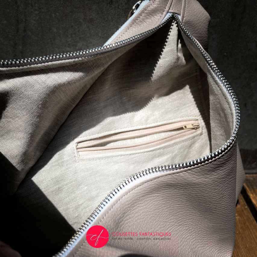 Un sac d'épaule triangulaire, constitué d'un simili beige et d'un tissu d'écharpe blanc, crème, beige et vert.