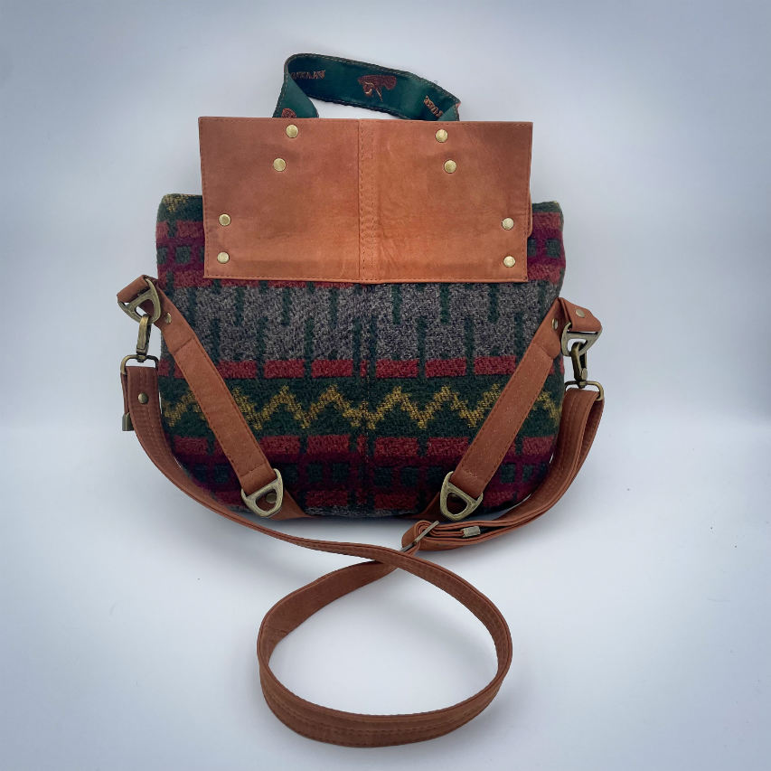 Un sac de taille moyenne, porté épaule, main, bandoulière ou dos, en suédine alezan et drap laine au motif géométrique, avec une doublure en viscose molletonée motif géométrique.