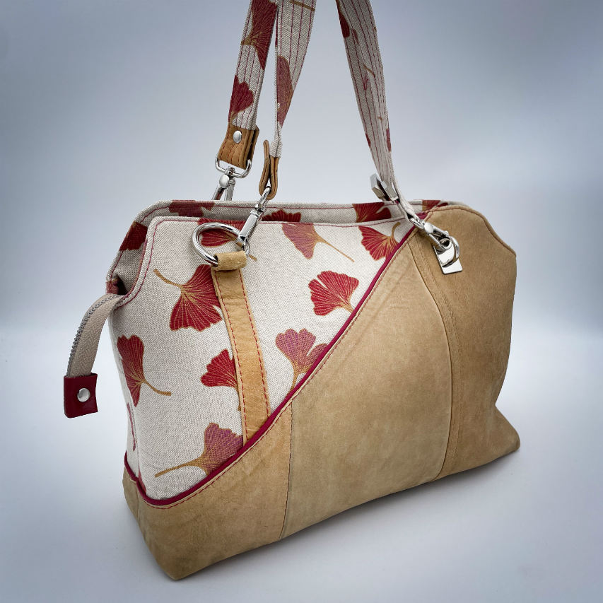 Un sac à main fait d'un cuir de couleur camel et une toile en polycoton avec un motif de feuilles de Ginkgo Biloba rouges.