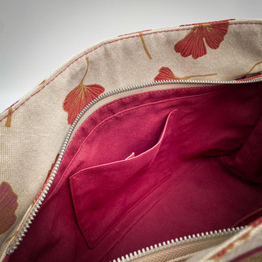 Un sac à main fait d'un cuir de couleur camel et une toile en polycoton avec un motif de feuilles de Ginkgo Biloba rouges.