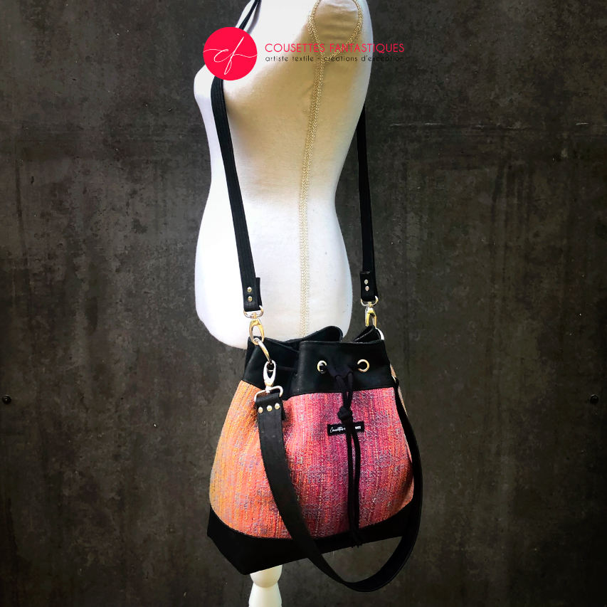 Un sac d'épaule fait en écharpe de portage dégradé miroir rose à bleu et liège noir.