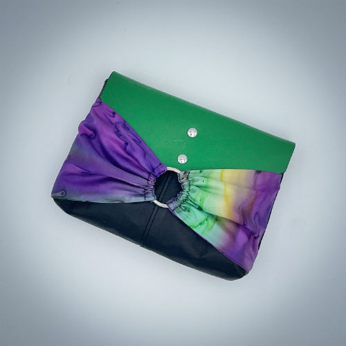 Une pochette à rabat cousue dans un voile de soie jaune, vert et violet et associé à des cuirs noir, vert et jaune.