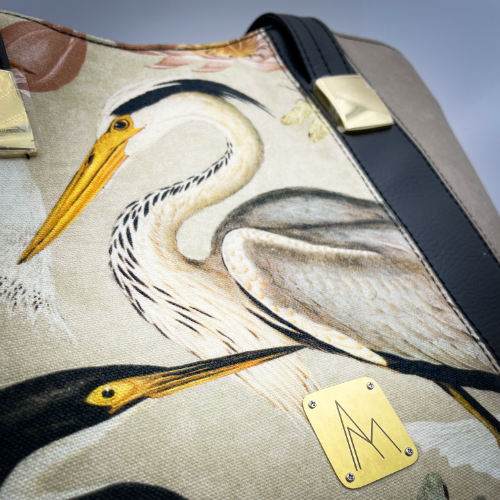 Un grand sac d'épaule type cabas zippé, fabriqué à partir d'un tissu épais au motif d'oiseaux sauvages associé à des simili noir et taupe, et une doublure lin crème chiné et corail.