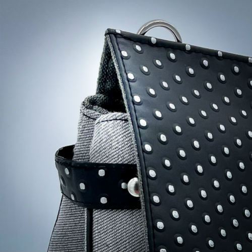 Un sac carré confectionné avec un simili noir à pois argentés et un denim couture gris.