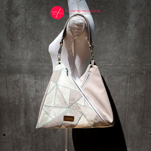 Un sac d'épaule triangulaire, constitué d'un simili beige et d'un tissu d'écharpe blanc, crème, beige et vert.