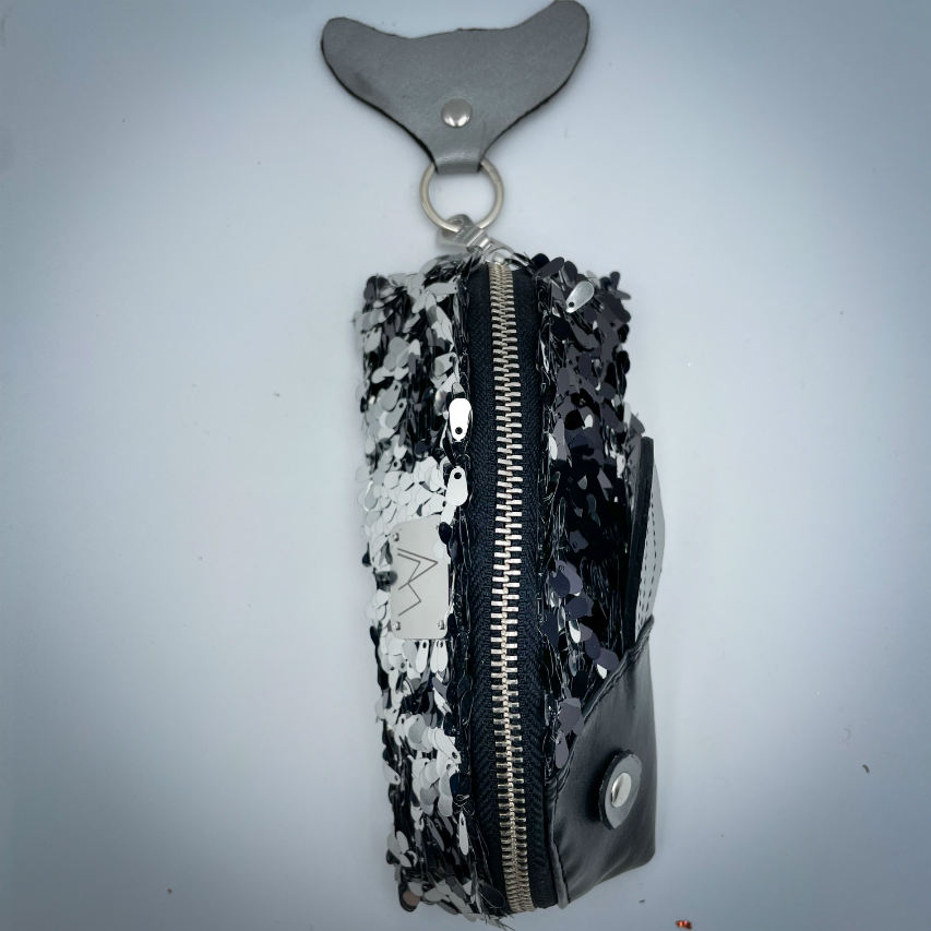 Une pochette zippée cousue dans du simili cuir noir, du tissu à sequins noirs et blancs, et du denim gris.