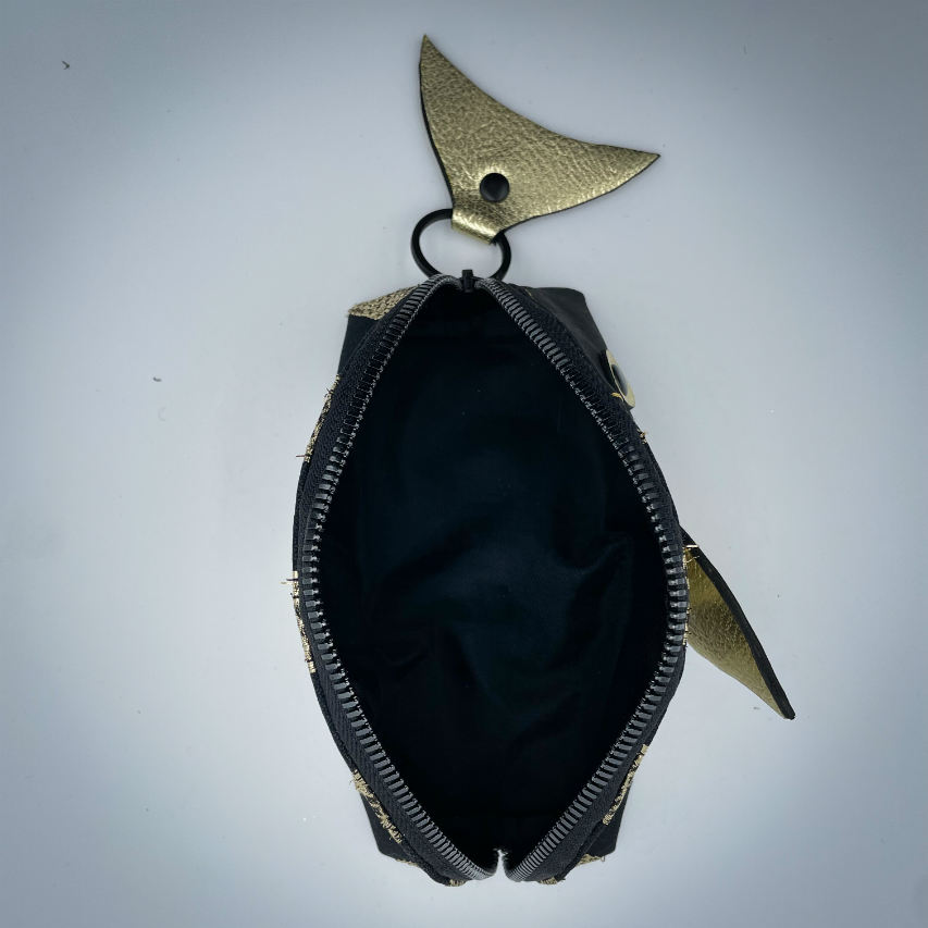 Une pochette zippée cousue dans du liège noir, du voile noir avec des bandes dorées et du cuir métallisé doré.