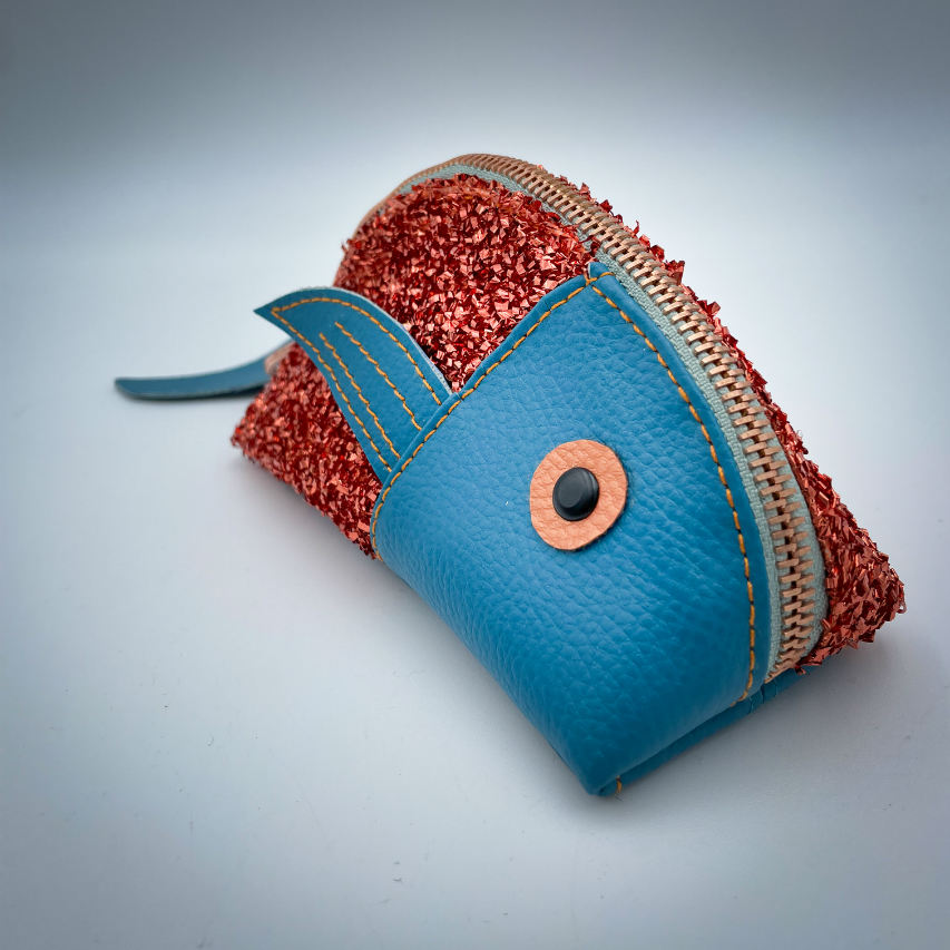 Une pochette zippée fabriquée à partir d'un tissu extensible avec du bouclé métallique cuivré, du similicuir bleu turquoise, et une doublure menthe clair.